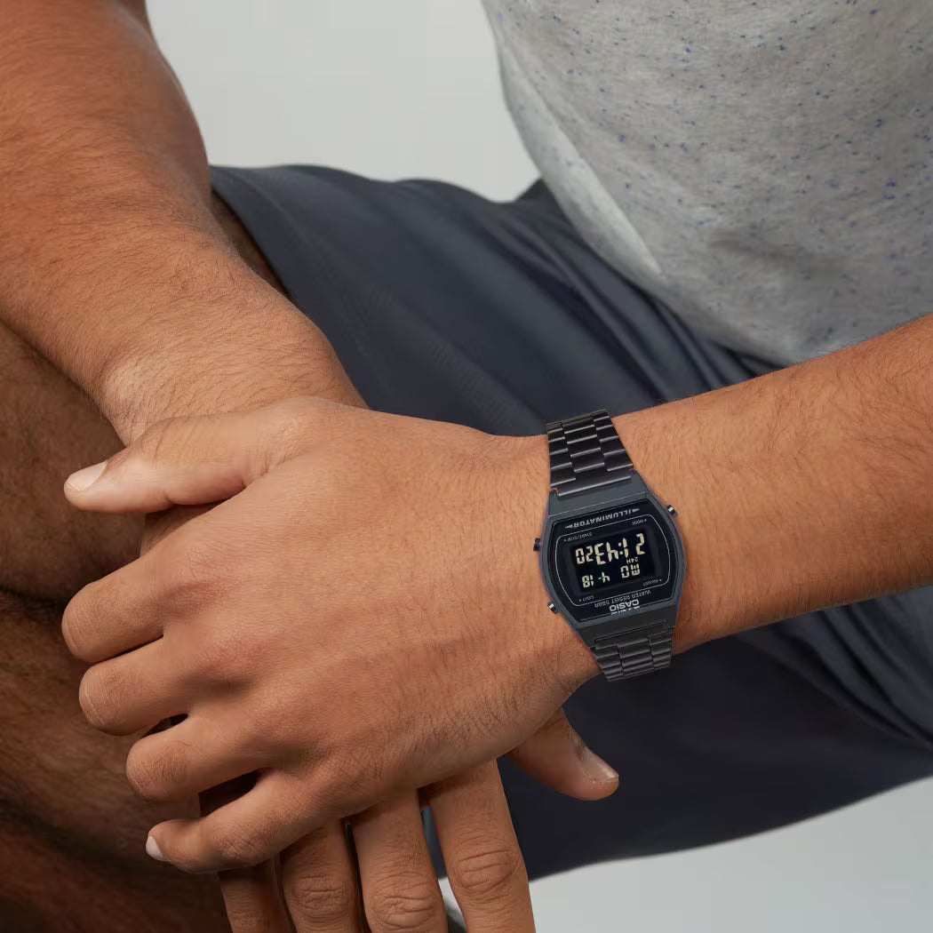 Person wearing a black digital watch on wrist with blurred background