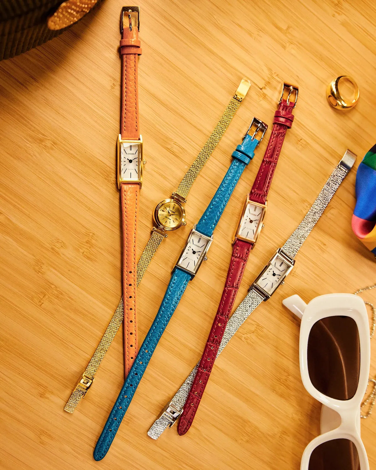 Collection of watches with different colored straps on a wooden surface.