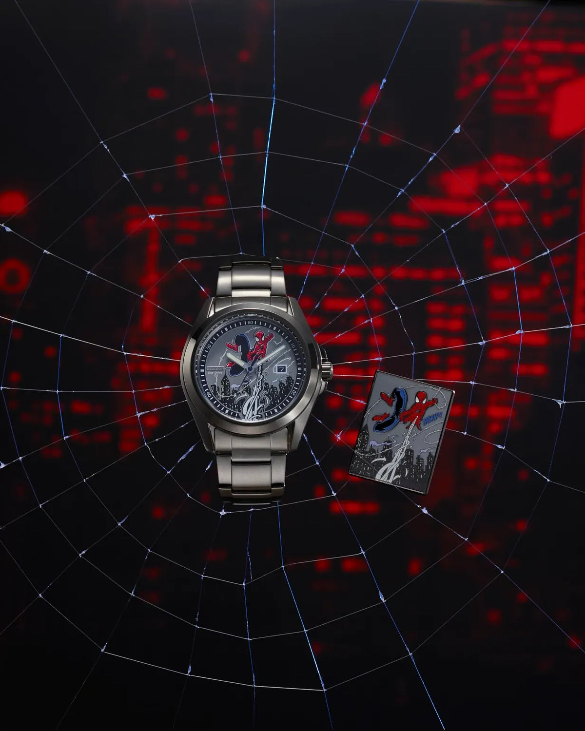 A silver-toned Spider-Man wristwatch with a detailed Spider-Man graphic dial, displayed next to a Spider-Man themed card on a dark background with a web pattern and red glowing city lights.