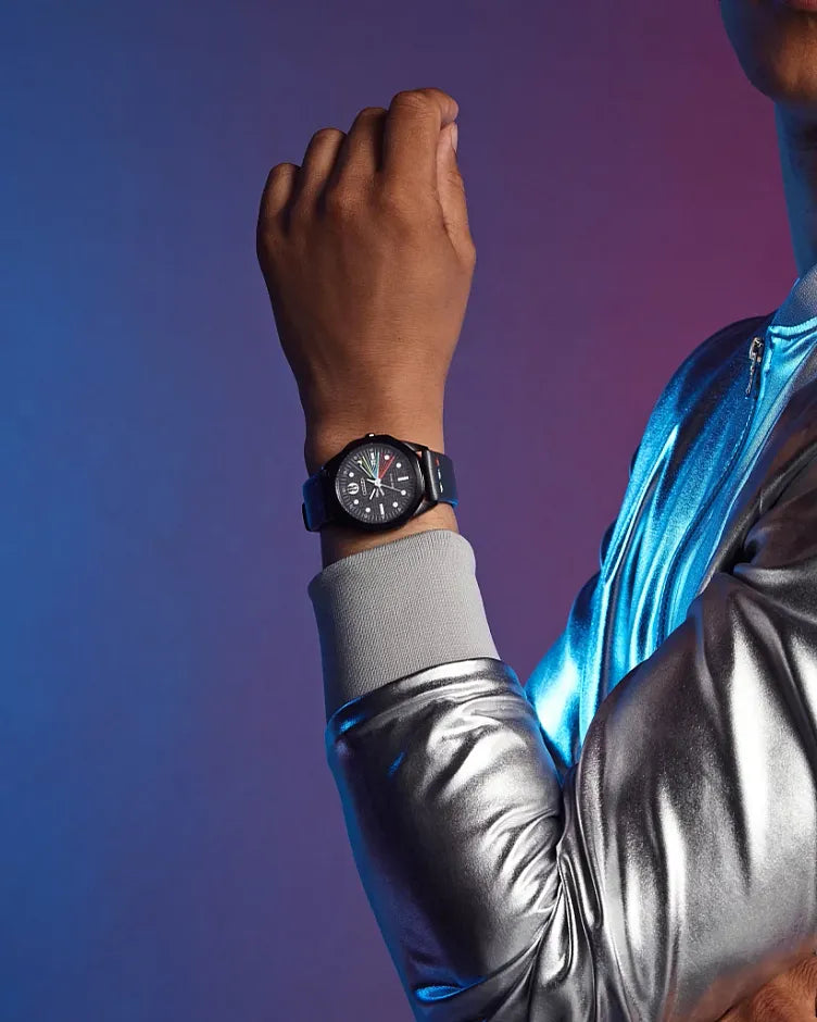 Person wearing a futuristic silver jacket with a watch on a gradient blue to purple background