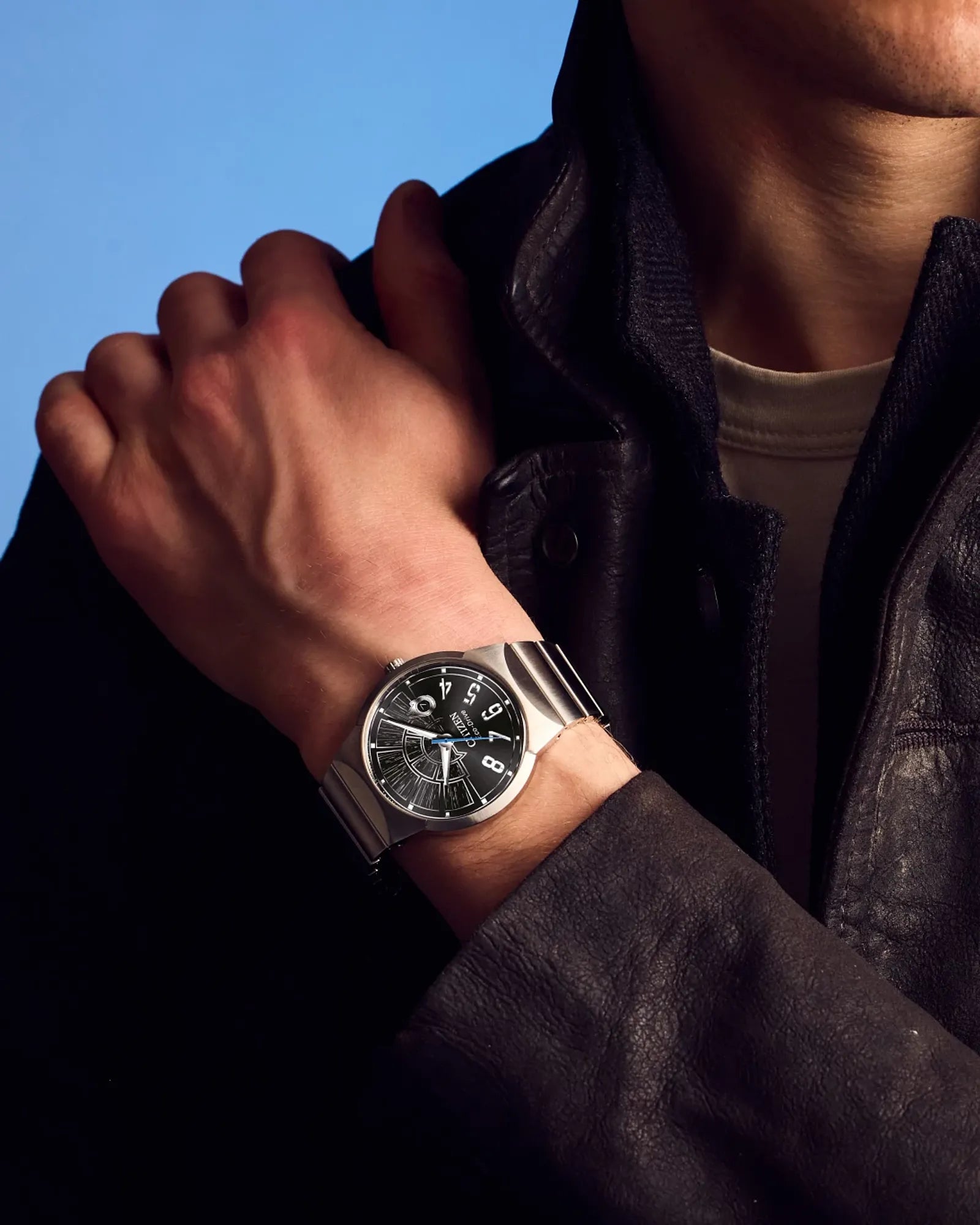 Person wearing a silver watch with a blue background