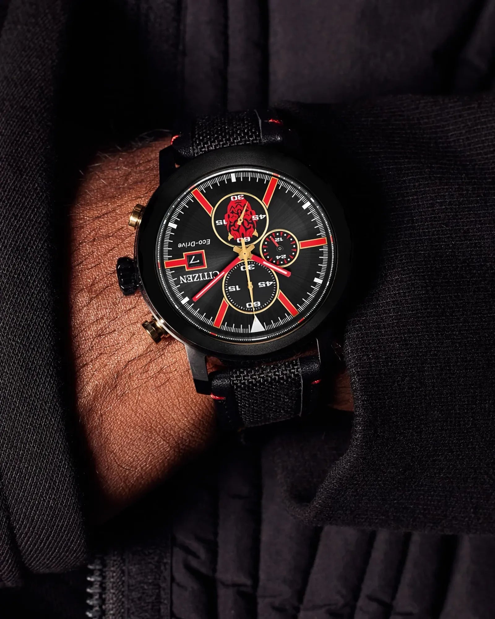 Black watch with red accents on a person's wrist against a dark background
