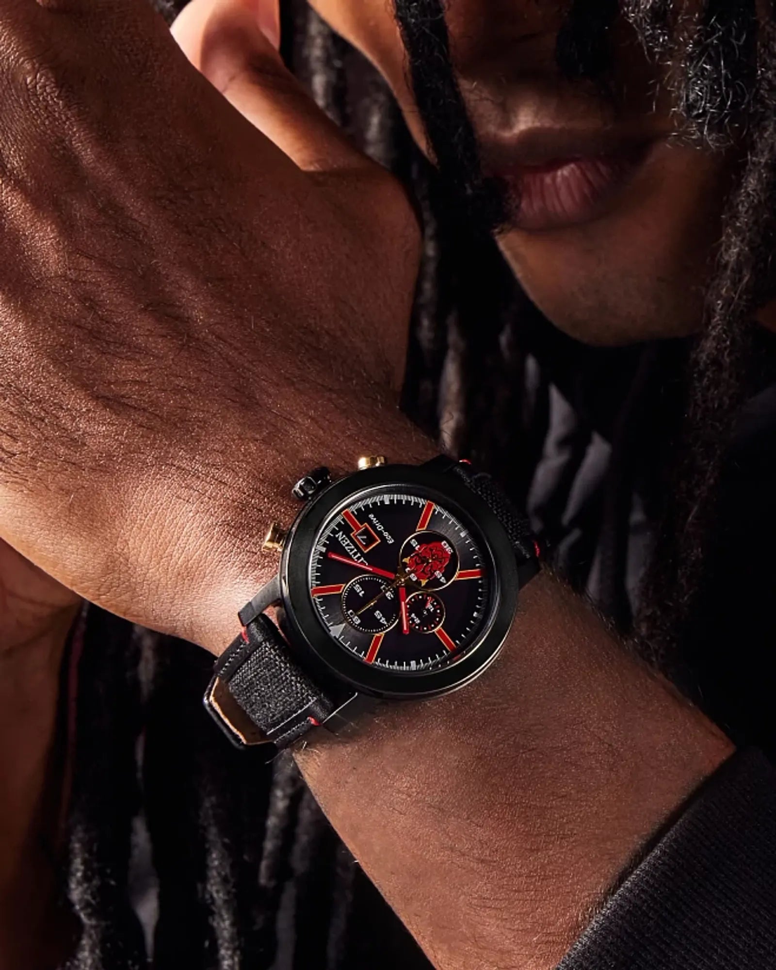 Person wearing a black watch with red accents on a dark background