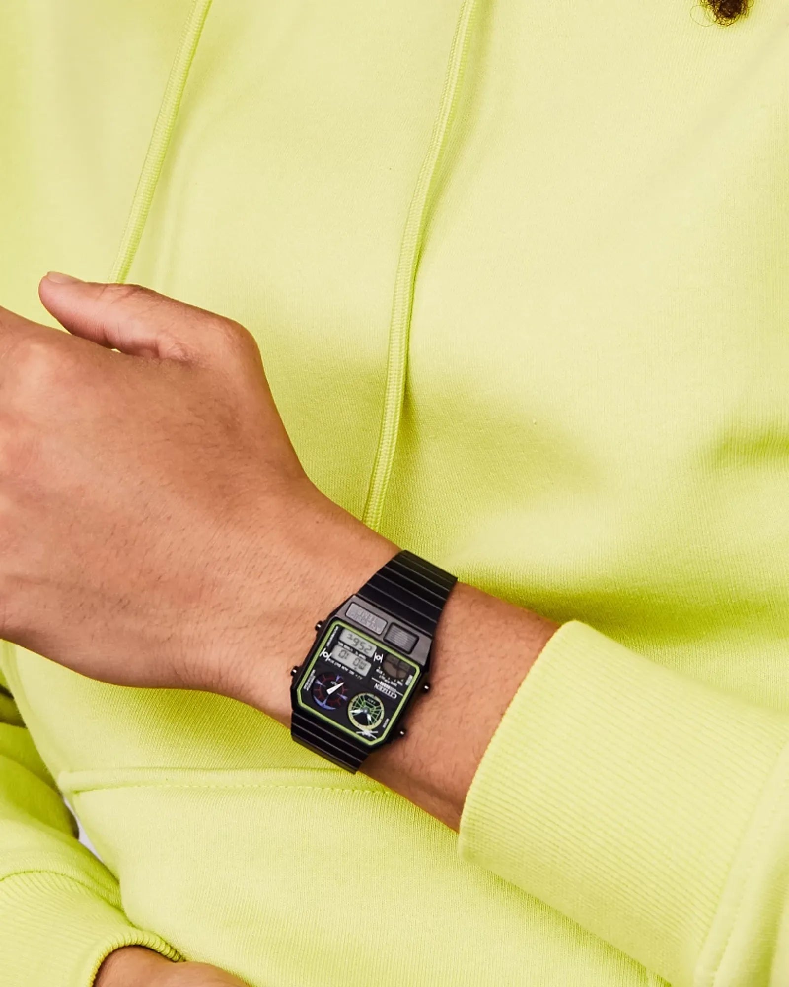 Person wearing a black digital watch on a light green background