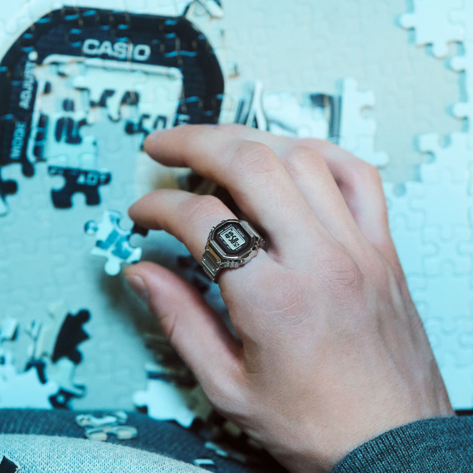Hand wearing a Casio watch with a ring, working on a puzzle.
