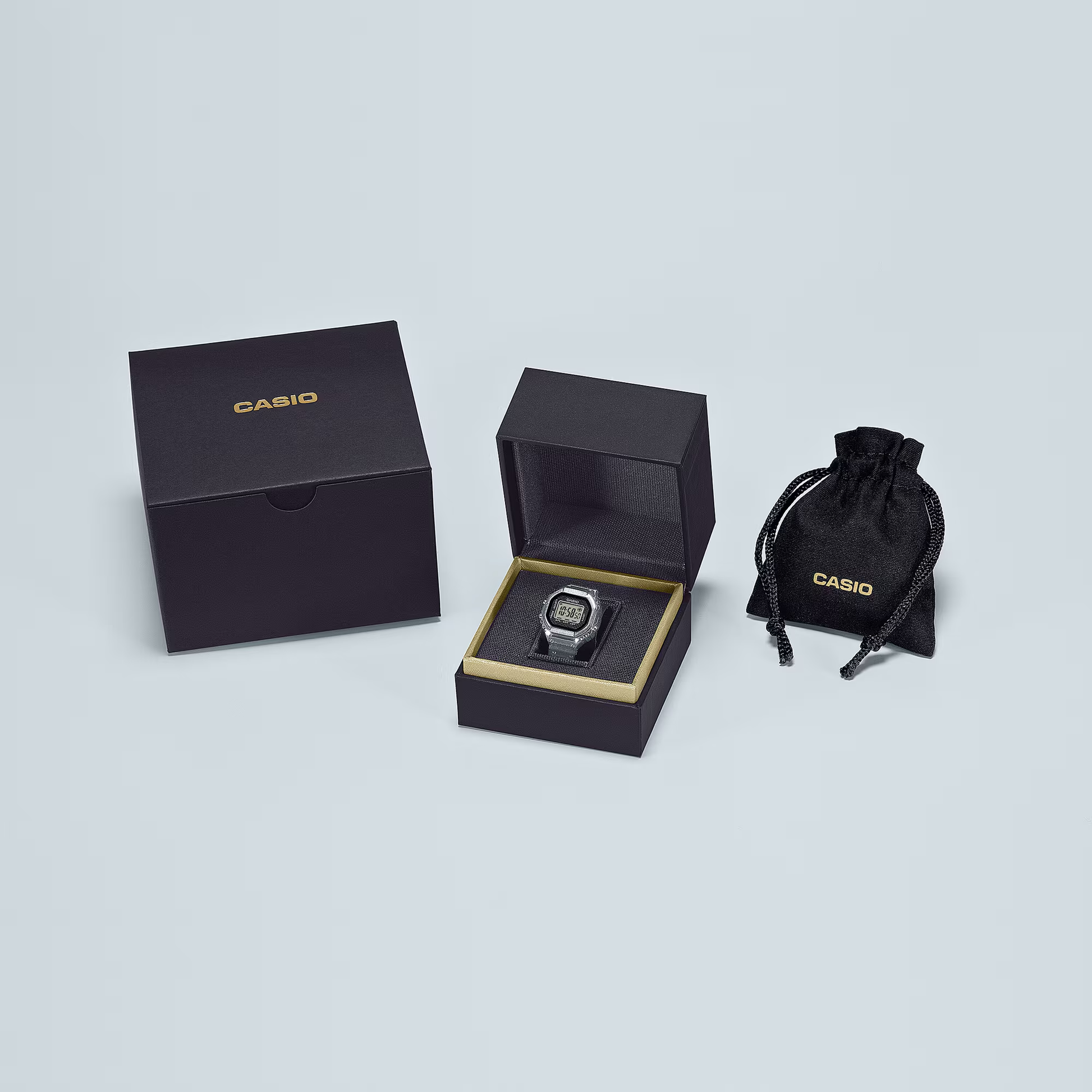 Casio watch in an open black box with a closed box and drawstring bag on a light gray background