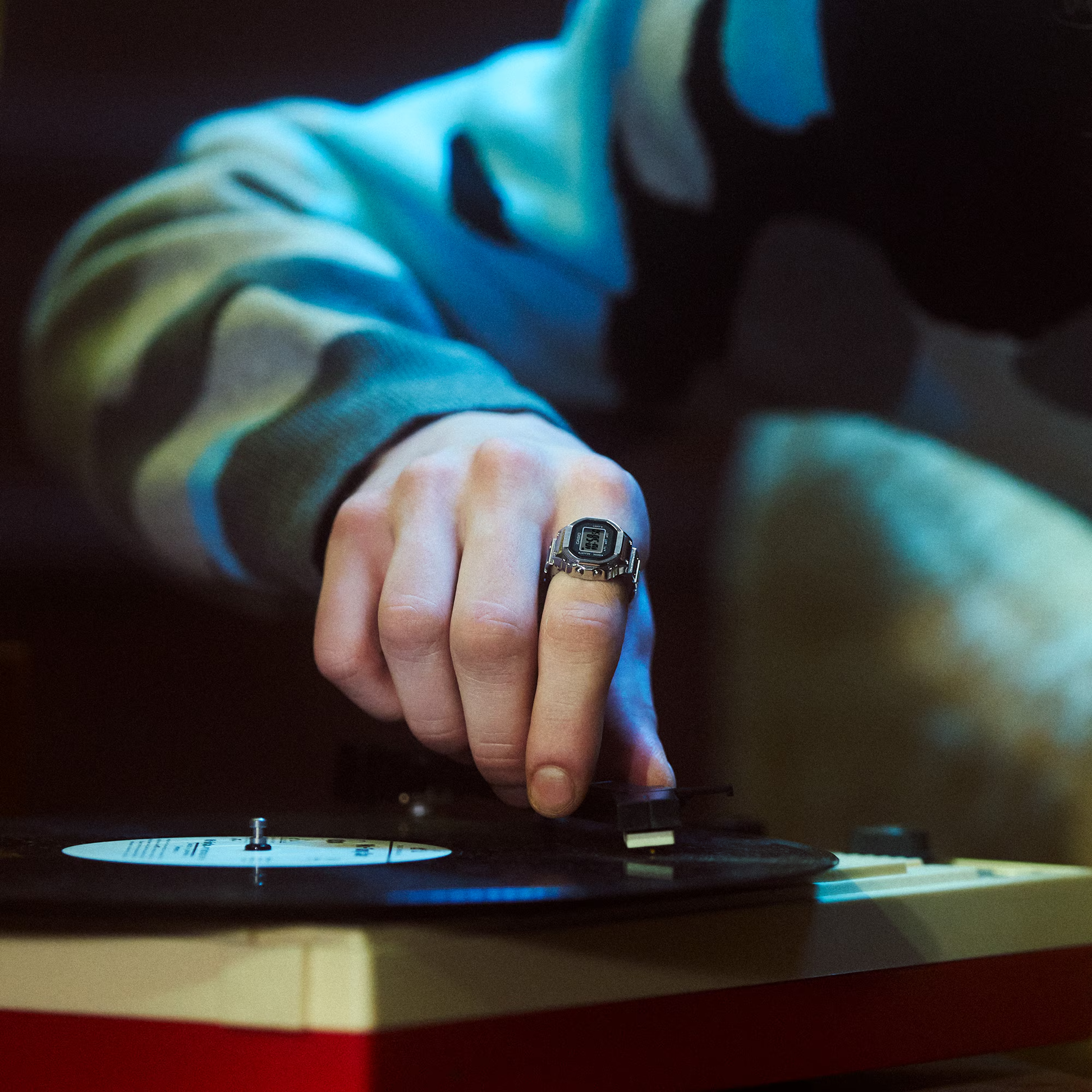 Person's hand with a ring on a vinyl record player