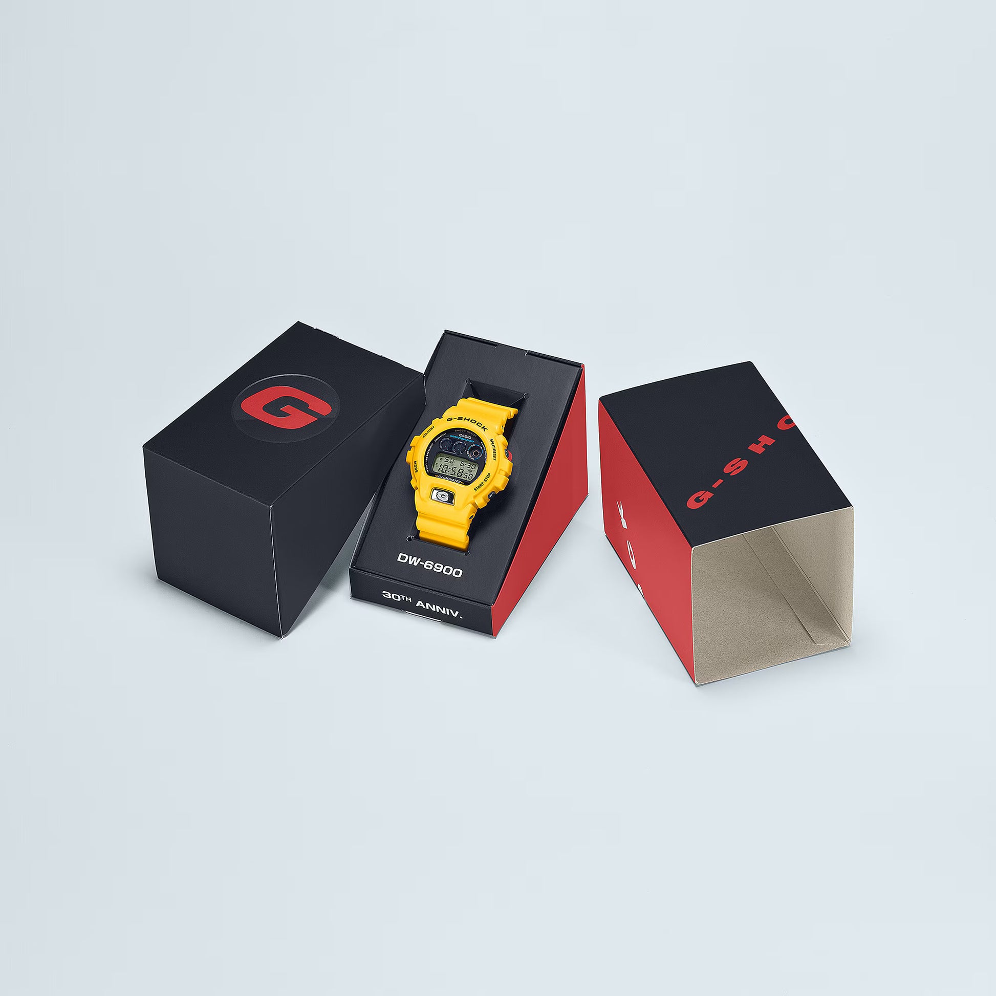 Yellow digital watch in a black and red box on a light gray background