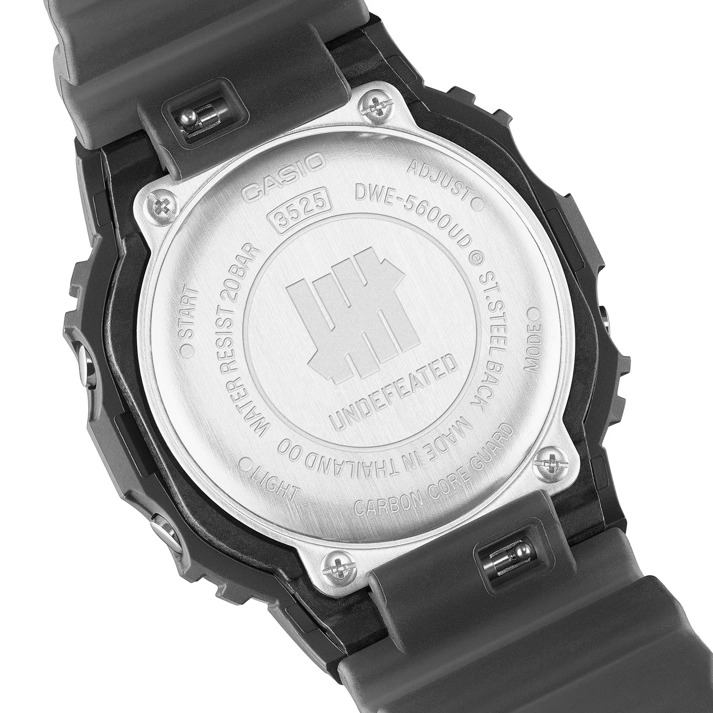 Casio G-SHOCK DWE5600UD-1 UNDEFEATED collaboration model with matte black Carbon Core Guard case, semi-translucent resin band featuring UNDEFEATED logo, green LCD display, engraved caseback, and special packaging. Includes two interchangeable camouflage straps (tiger camo, storm camo). Features shock resistance, mineral glass, 200m water resistance, LED Super Illuminator backlight, stopwatch, countdown timer, alarms, flash alert, auto-calendar, and ±15 sec/month accuracy. Case size 48.9 × 43.8 × 13.7 mm, we
