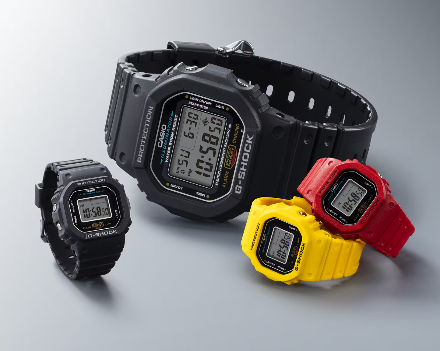 Four Casio G-Shock watches in black, yellow, red, and gray on a light gray background
