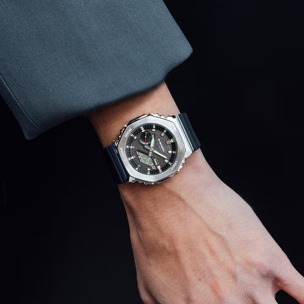 Wrist wearing a silver and black watch with a dark background