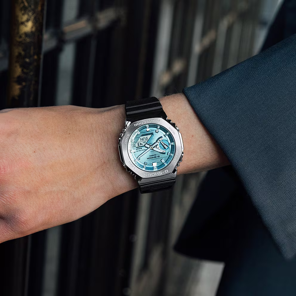 Person wearing a black wristwatch with a blue face on a blurred background