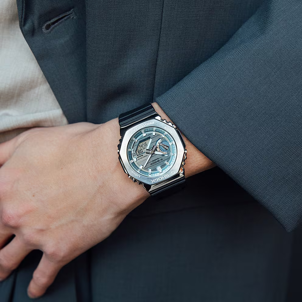 Close-up of a person wearing a stylish watch on a dark suit background