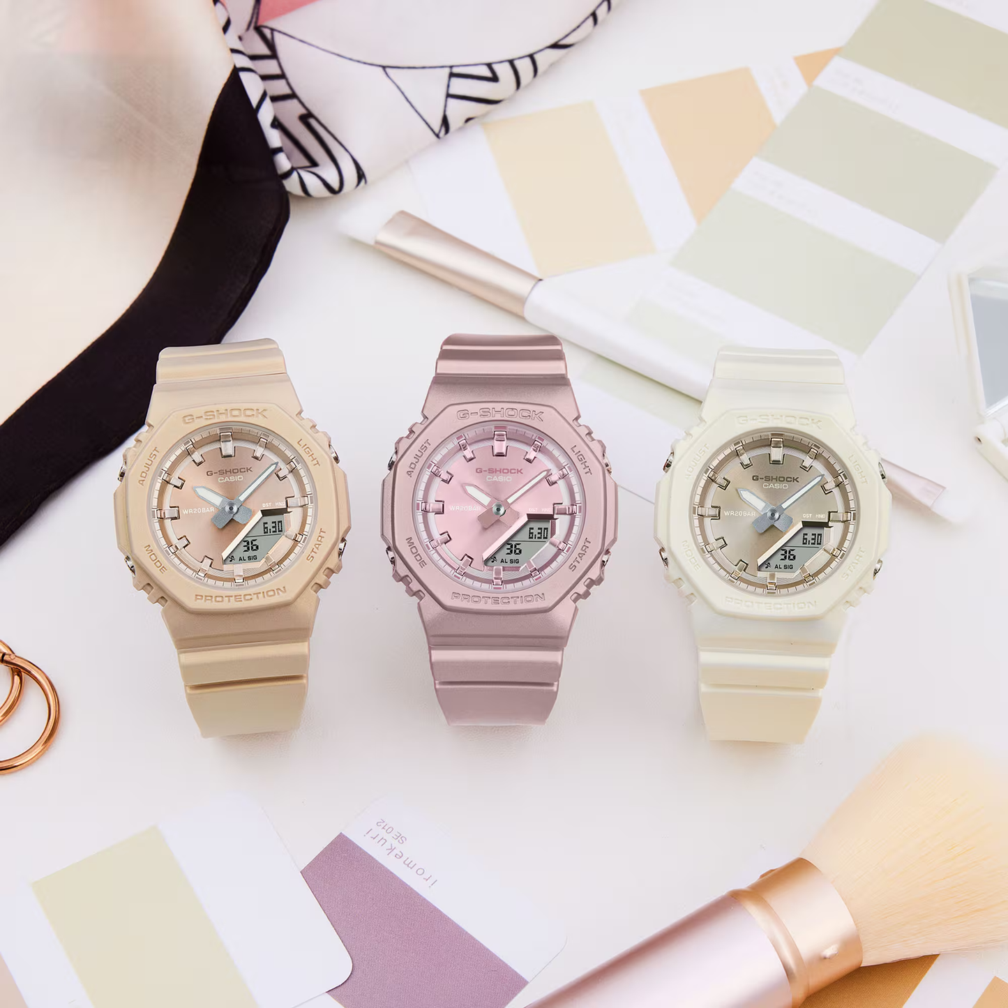 Three colorful watches on a white surface with a pen and paper.