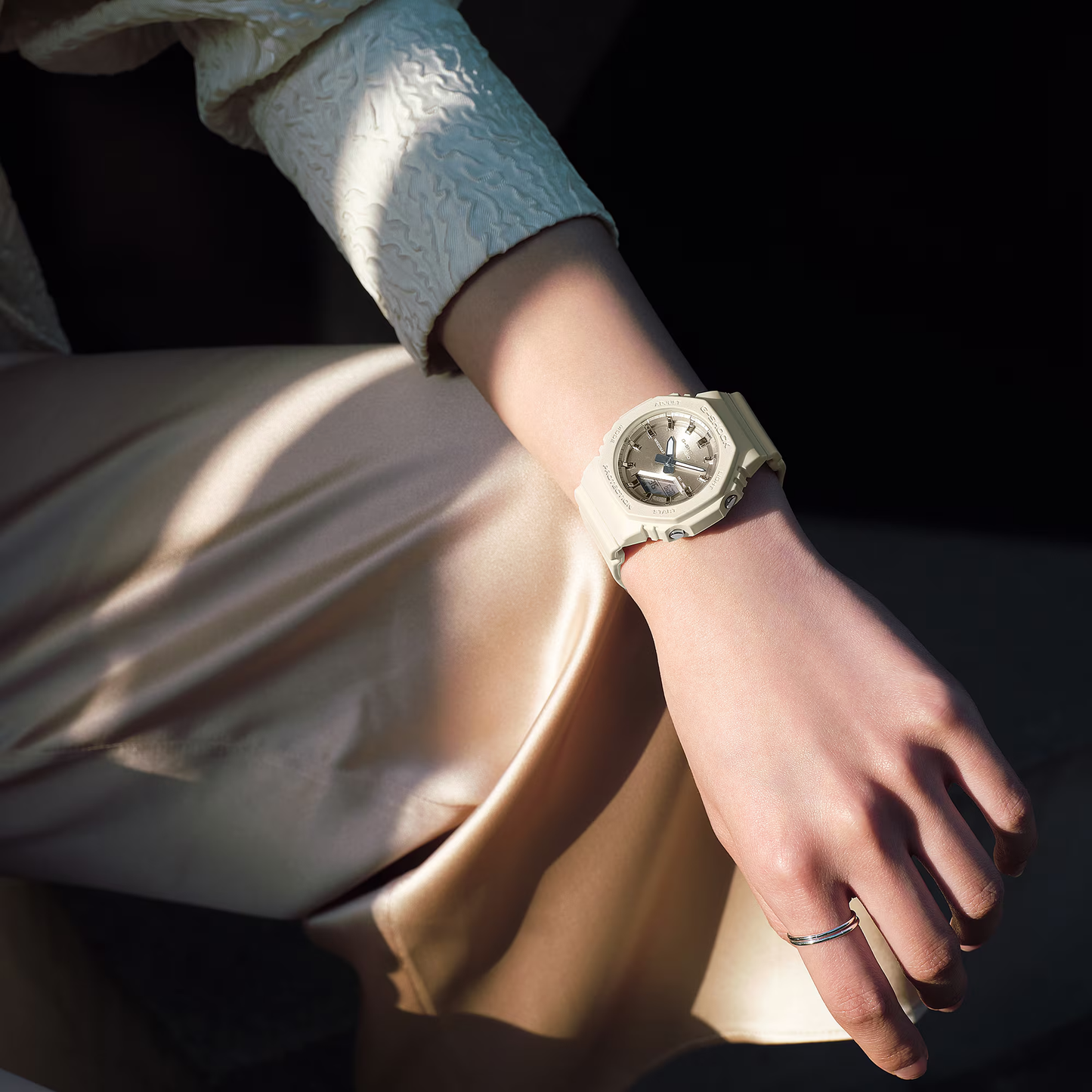 Close-up of a wrist wearing a silver watch with a dark background