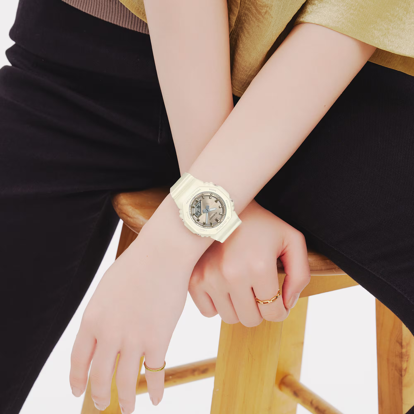 Person wearing a light-colored wristwatch on a white background