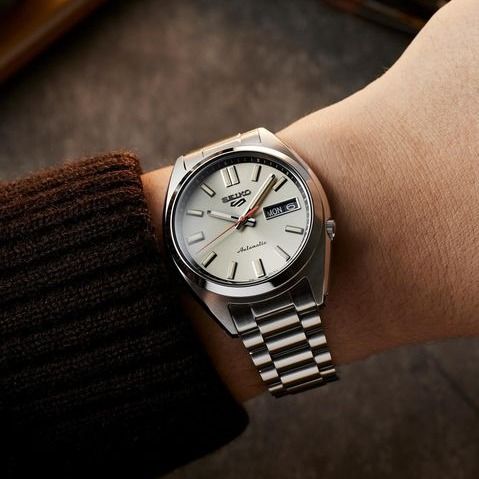 Seiko SRPK91 – ivory dial automatic watch from Seiko 5 Sports with diamond-cut indices, curved Hardlex crystal, see-through caseback, and 100m water resistance.