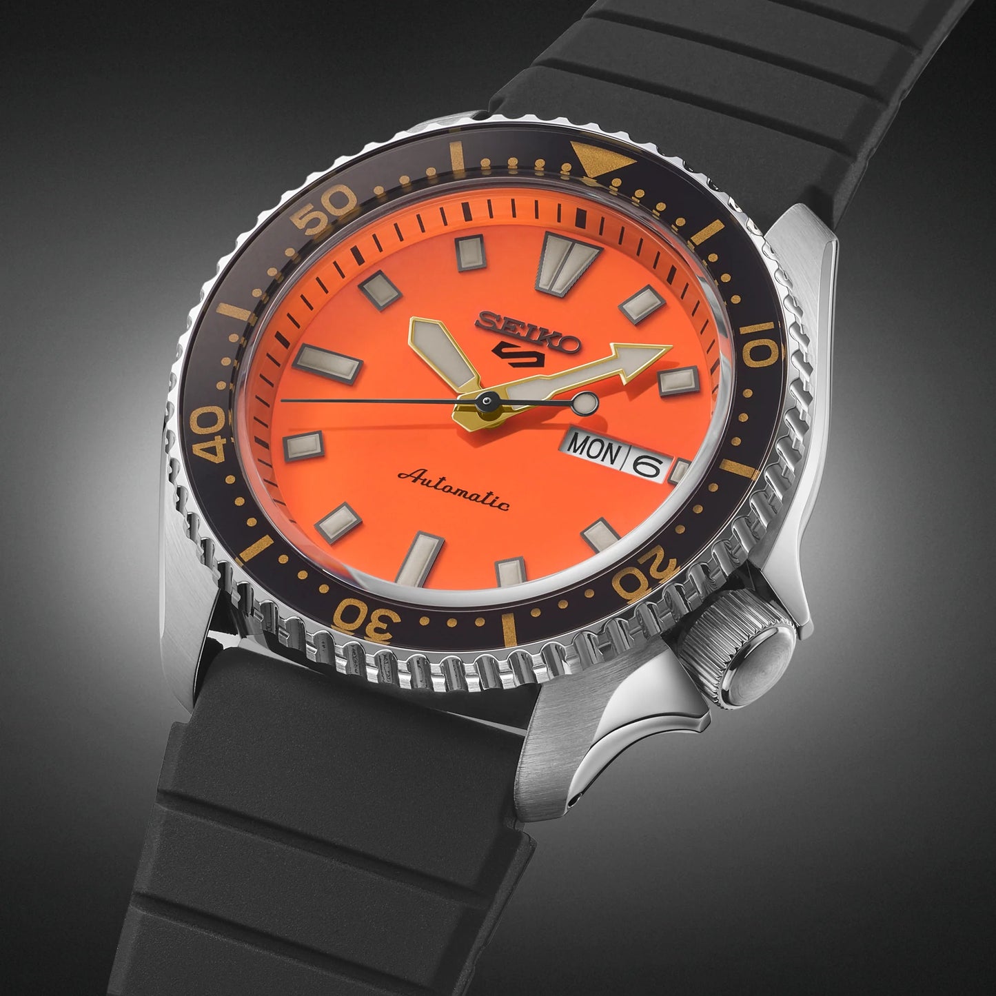 SEIKO 5 Sports SRPL89 SKX Sports Style – vivid orange dial, black rotating bezel with gold accents, black silicone strap, automatic movement, and 100m water resistance.