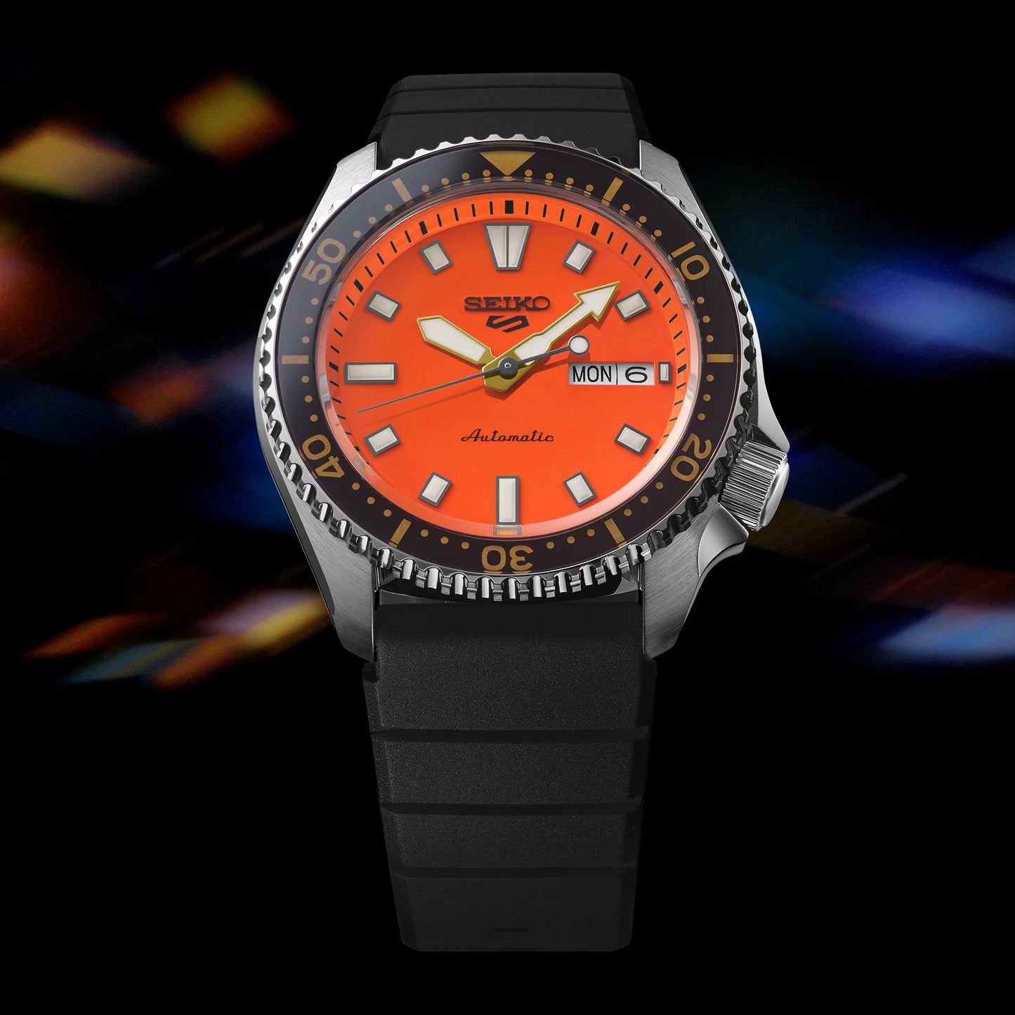 SEIKO 5 Sports SRPL89 SKX Sports Style – vivid orange dial, black rotating bezel with gold accents, black silicone strap, automatic movement, and 100m water resistance.