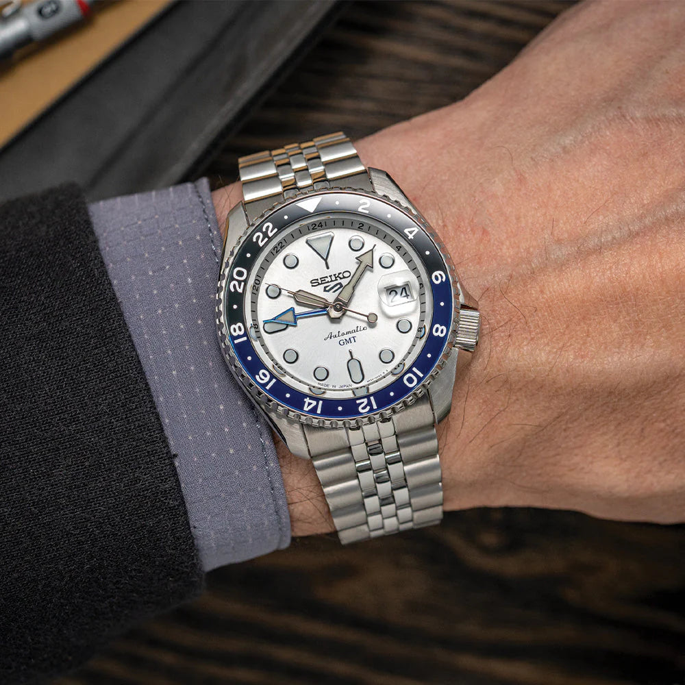 Seiko SSK033 GMT automatic watch with silver sunray dial, dual-tone blue and black 24-hour bezel, luminous hands, magnified date display, and stainless steel five-row bracelet — SKX-inspired GMT model available at Miseki Jewelry