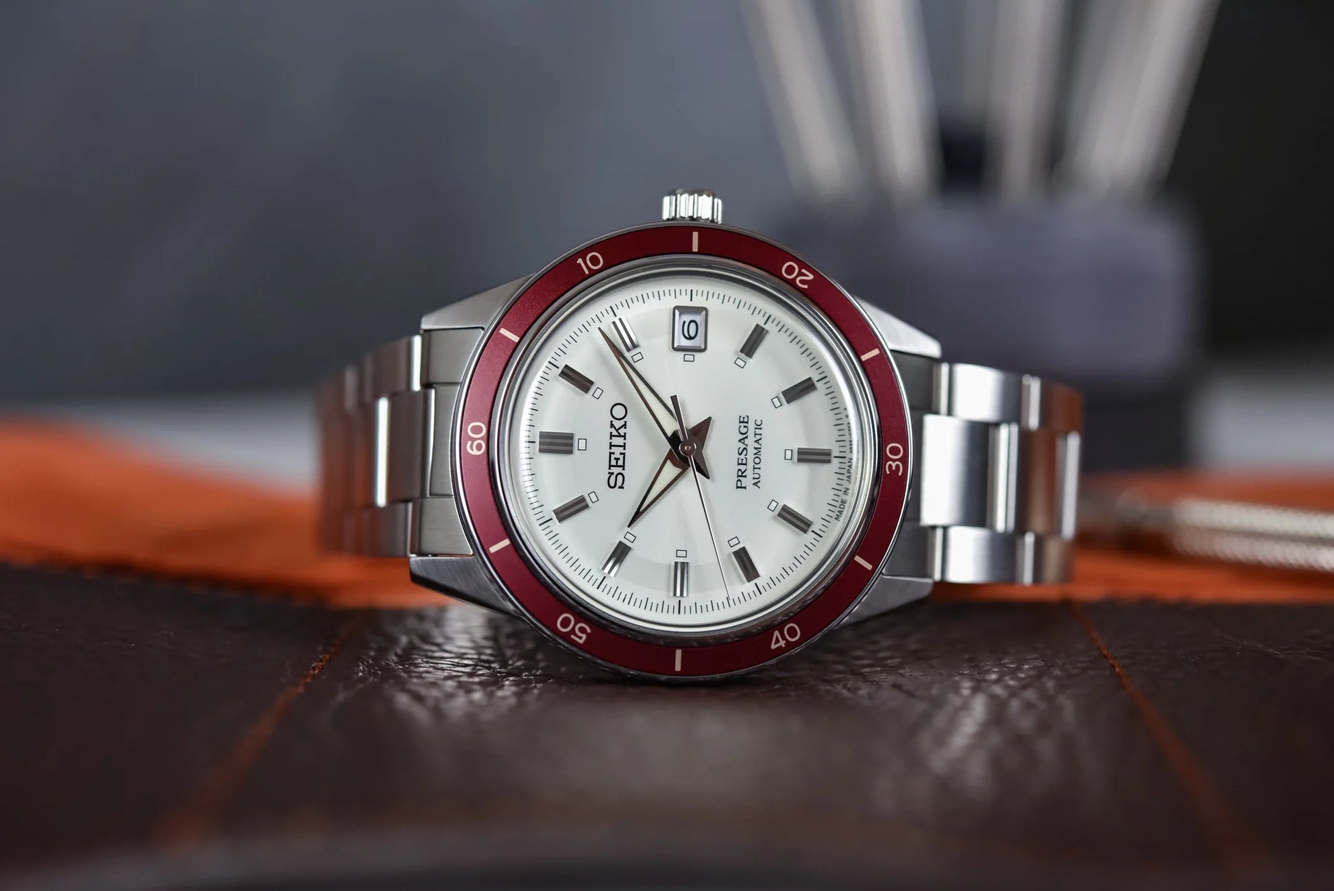 SEIKO SRPH93 from the Presage Style60’s Collection – ivory sunray dial, matte red bezel, stainless steel bracelet, automatic 23-jewel movement, and 50m water resistance.
