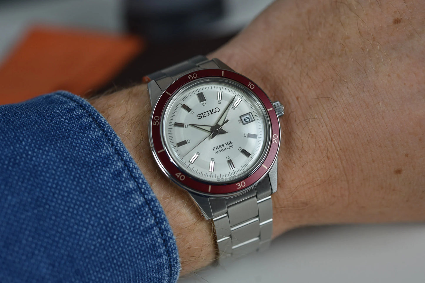 SEIKO SRPH93 from the Presage Style60’s Collection – ivory sunray dial, matte red bezel, stainless steel bracelet, automatic 23-jewel movement, and 50m water resistance.