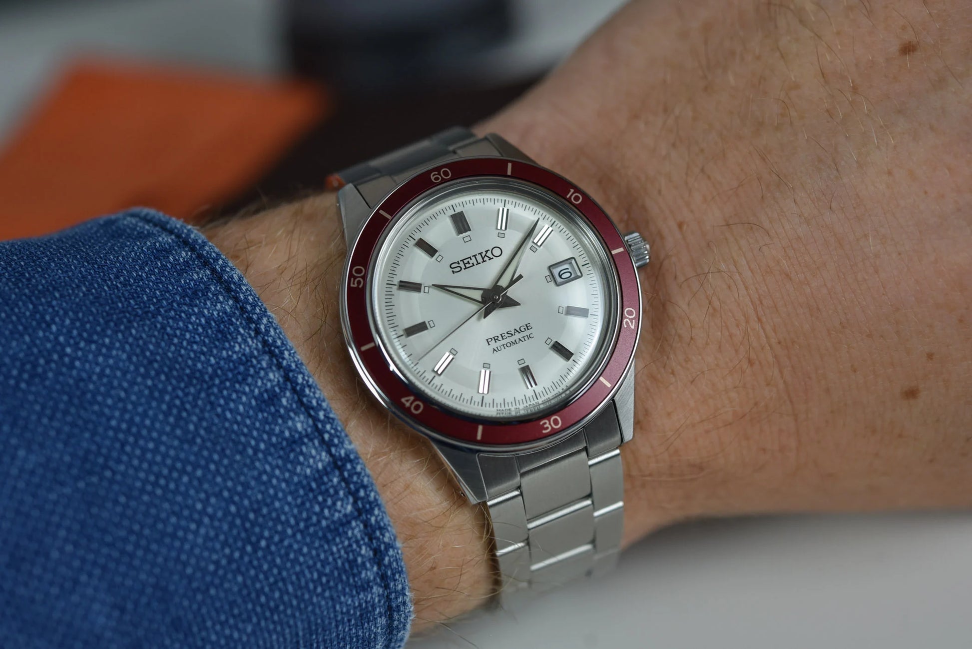 SEIKO SRPH93 from the Presage Style60’s Collection – ivory sunray dial, matte red bezel, stainless steel bracelet, automatic 23-jewel movement, and 50m water resistance.