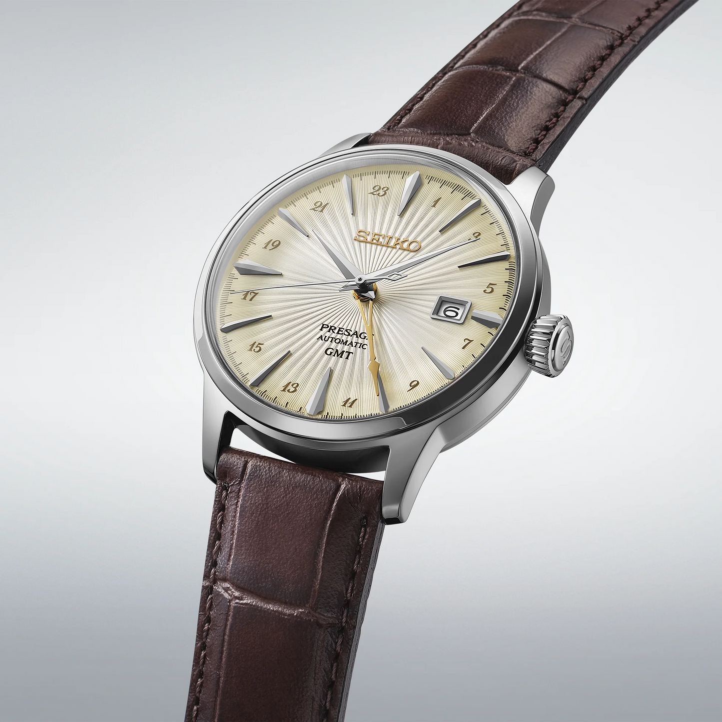 Seiko SSK041 – Presage Cocktail Time GMT watch with ivory patterned dial, gold-tone cocktail-glass-shaped GMT hand, see-through caseback, and brown leather strap; inspired by the Acacia cocktail.
