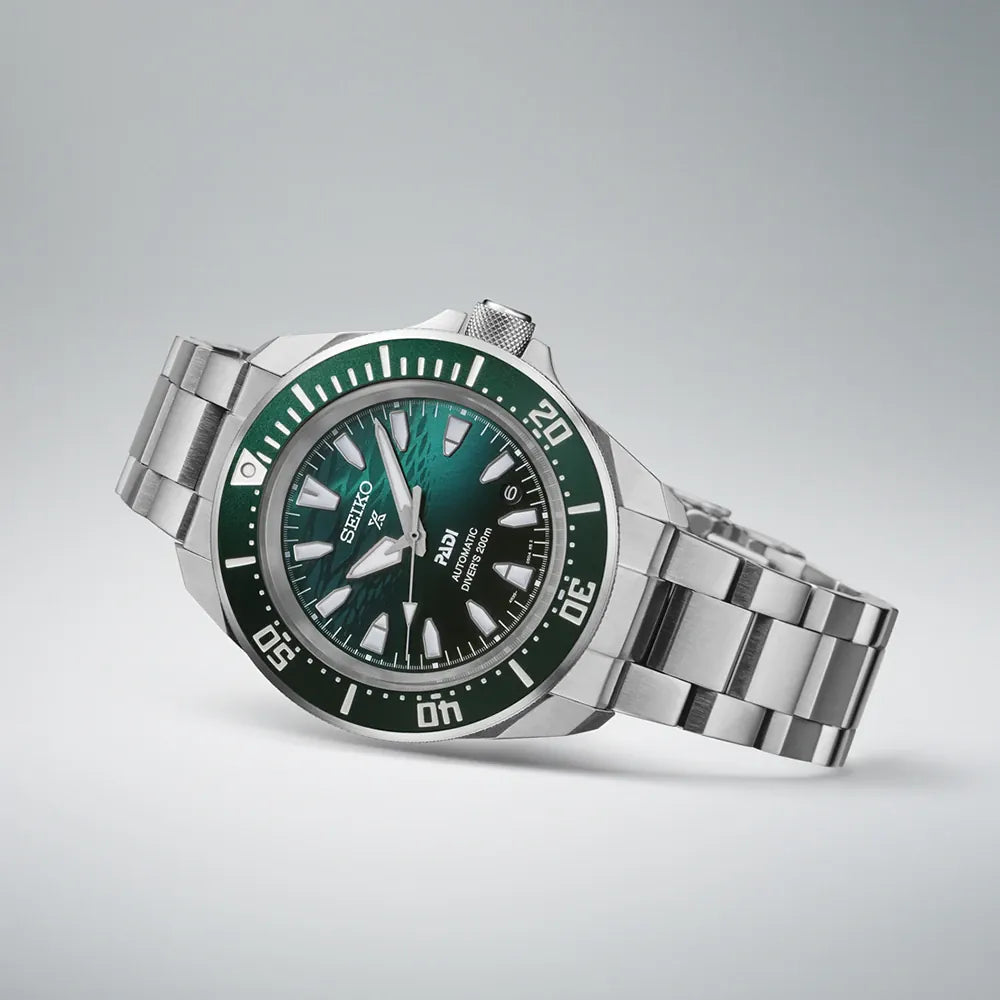 Seiko watch with green dial and silver bracelet on a light gray background