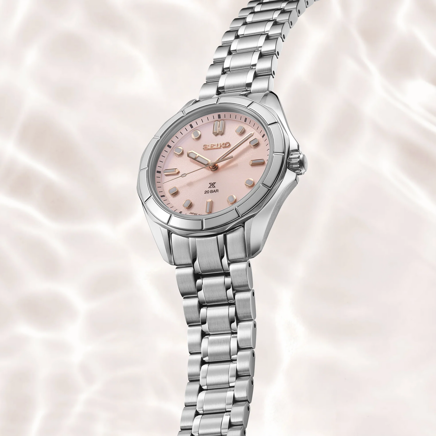 Silver Seiko watch with a pink face on a soft pink background