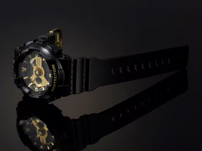 Black and gold watch with visible brand name on a dark background