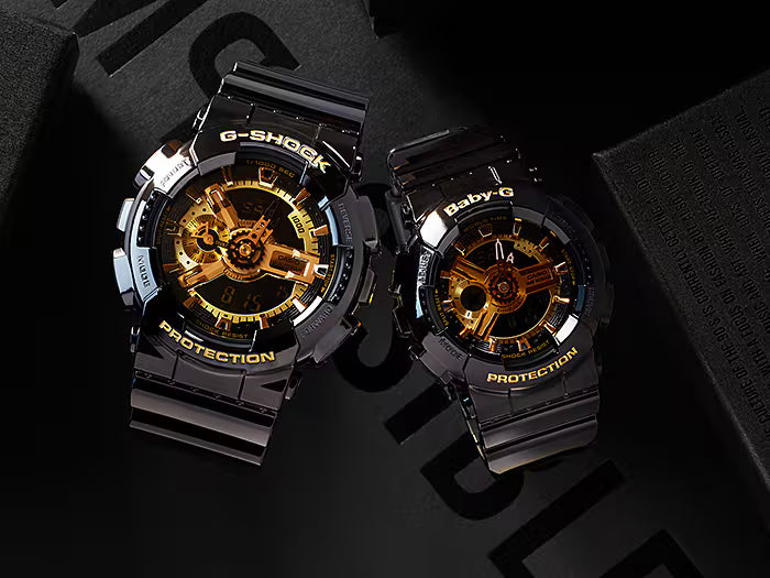 Two G-Shock watches with black and gold design on a dark background