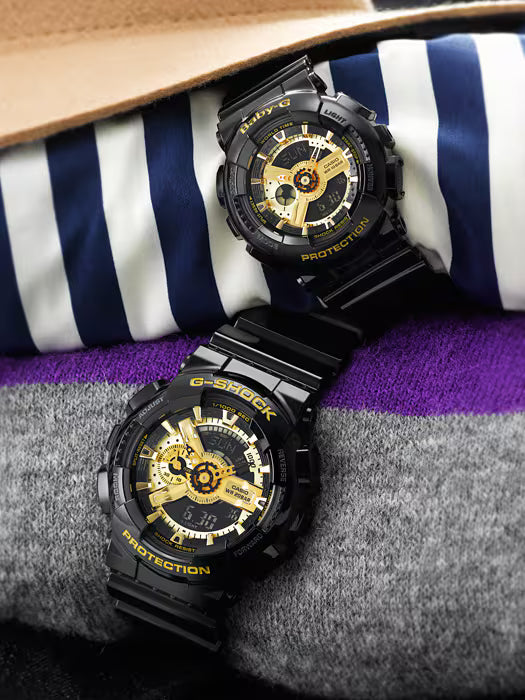 Black G-Shock watch with gold accents on a striped fabric background