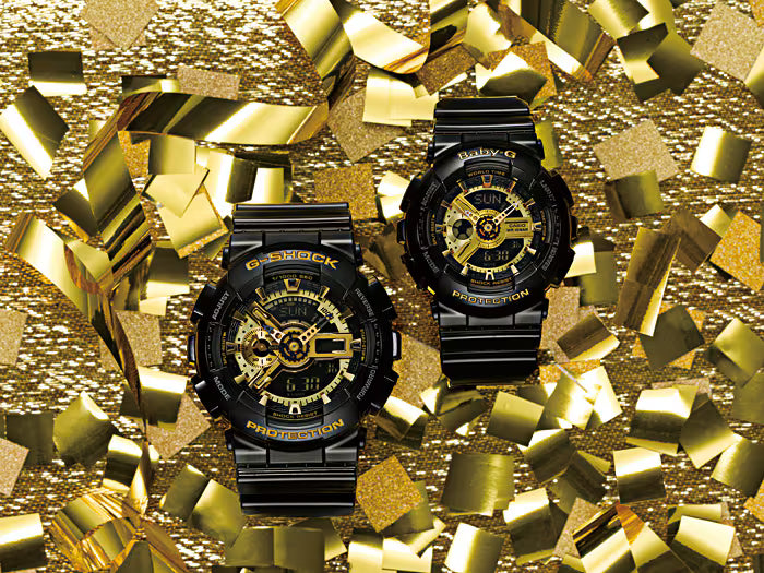 Two black watches with gold accents on a glittery gold background