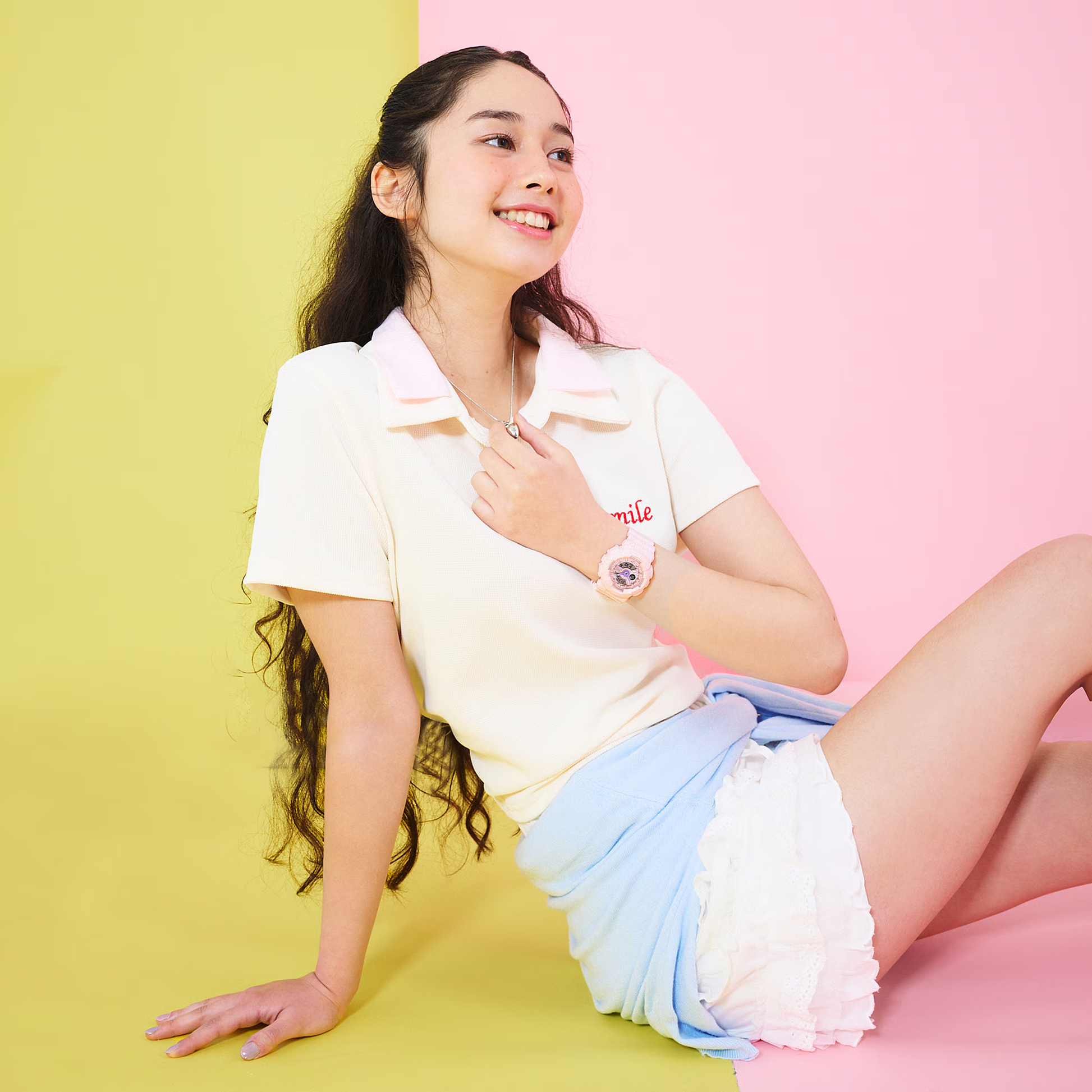 Woman in a pastel outfit sitting on a pink and yellow background
