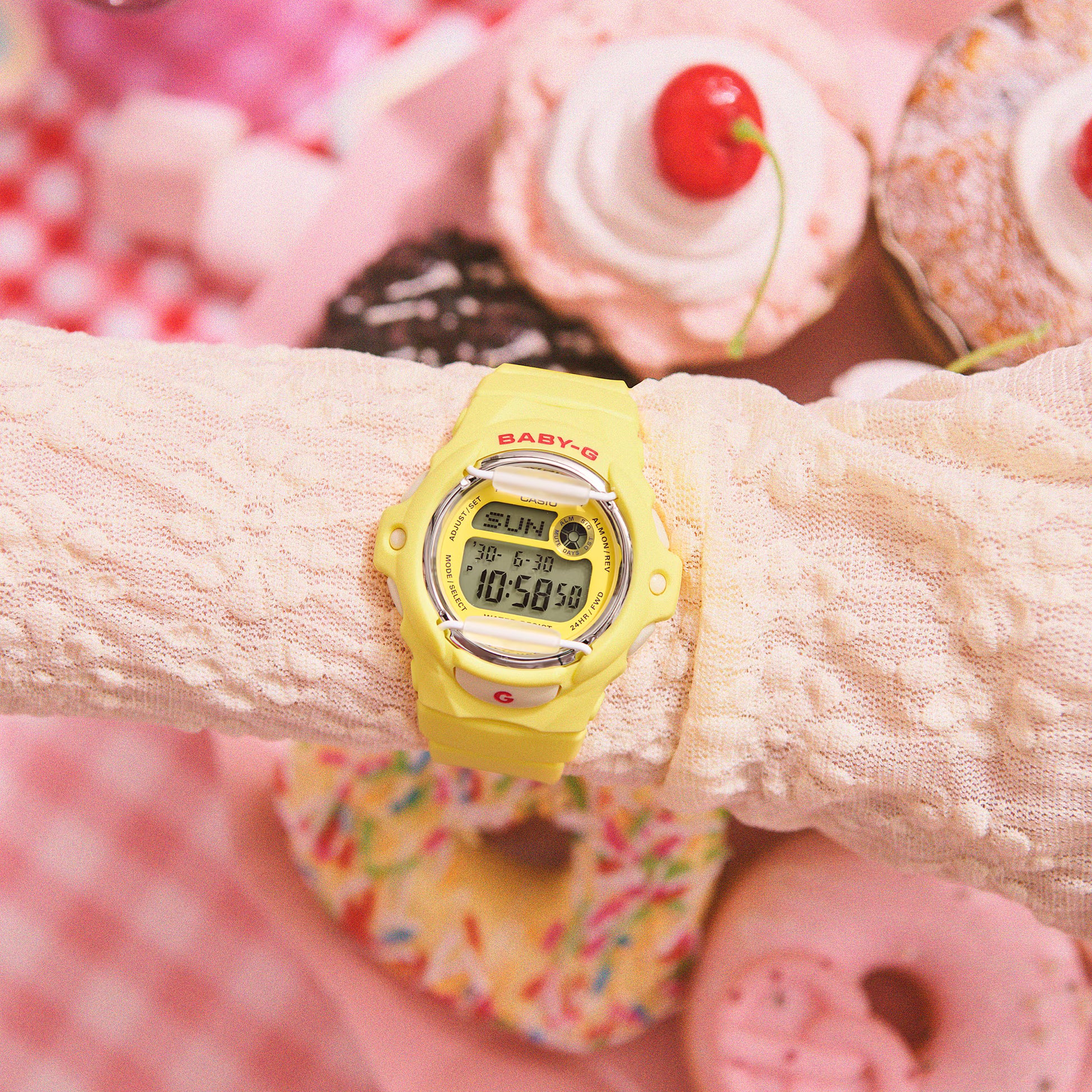 Yellow digital watch on a wrist with a colorful donut-themed background