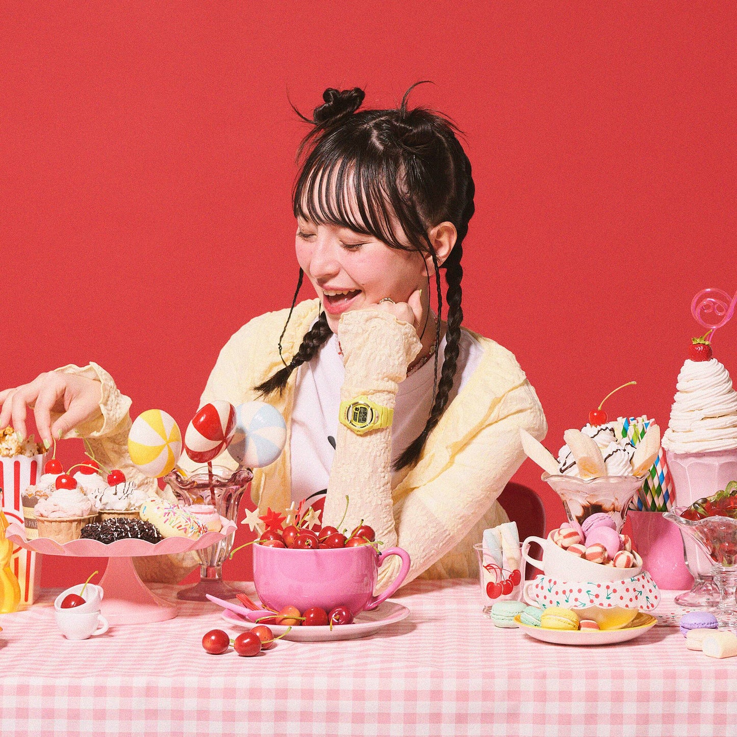 Person sitting at a table with various desserts against a red background