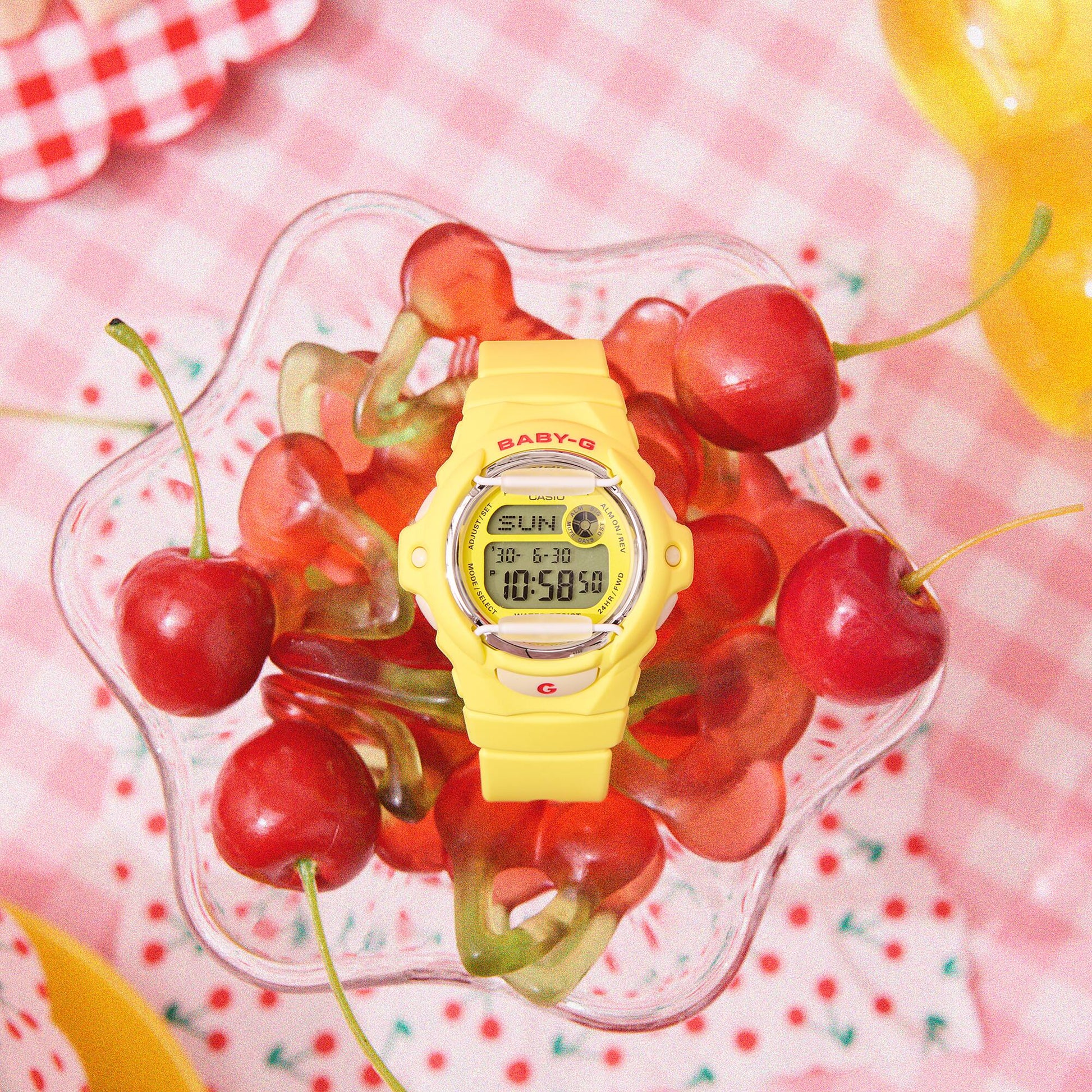 Yellow digital watch with red cherries on a pink checkered background