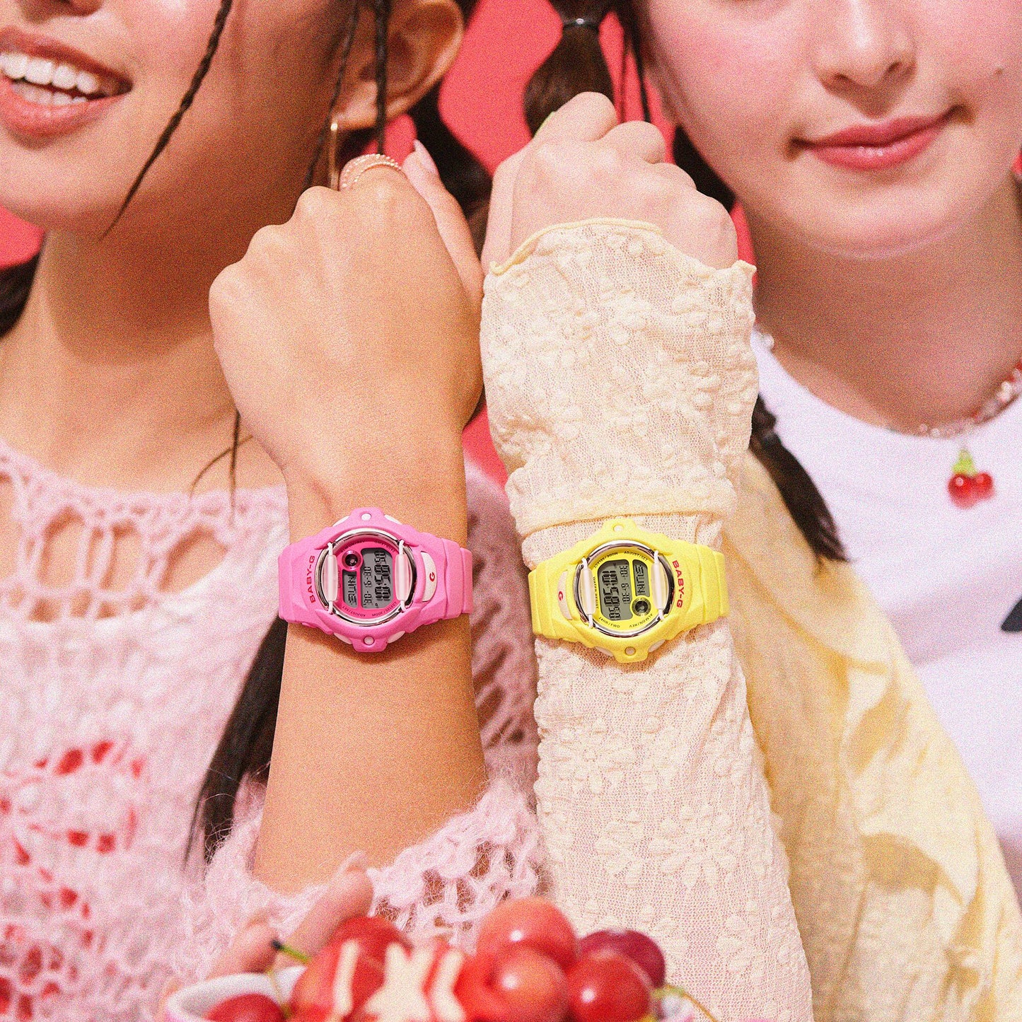 Two girls wearing colorful digital wristwatches, one pink and one yellow, with a close-up focus on their wrists.