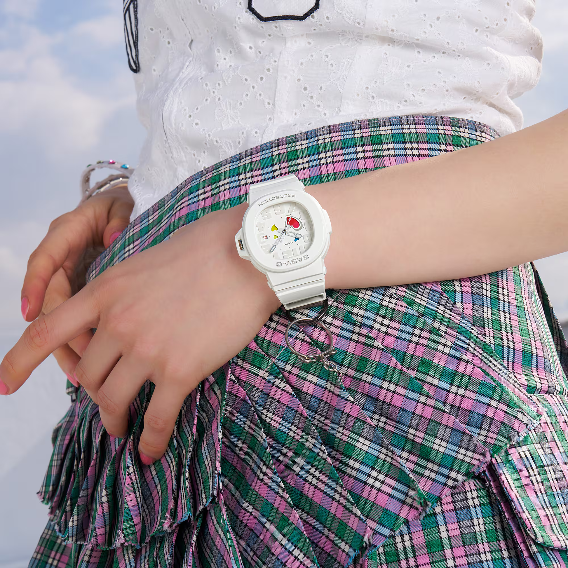 Person wearing a white Casio watch with colorful character design on a plaid skirt.