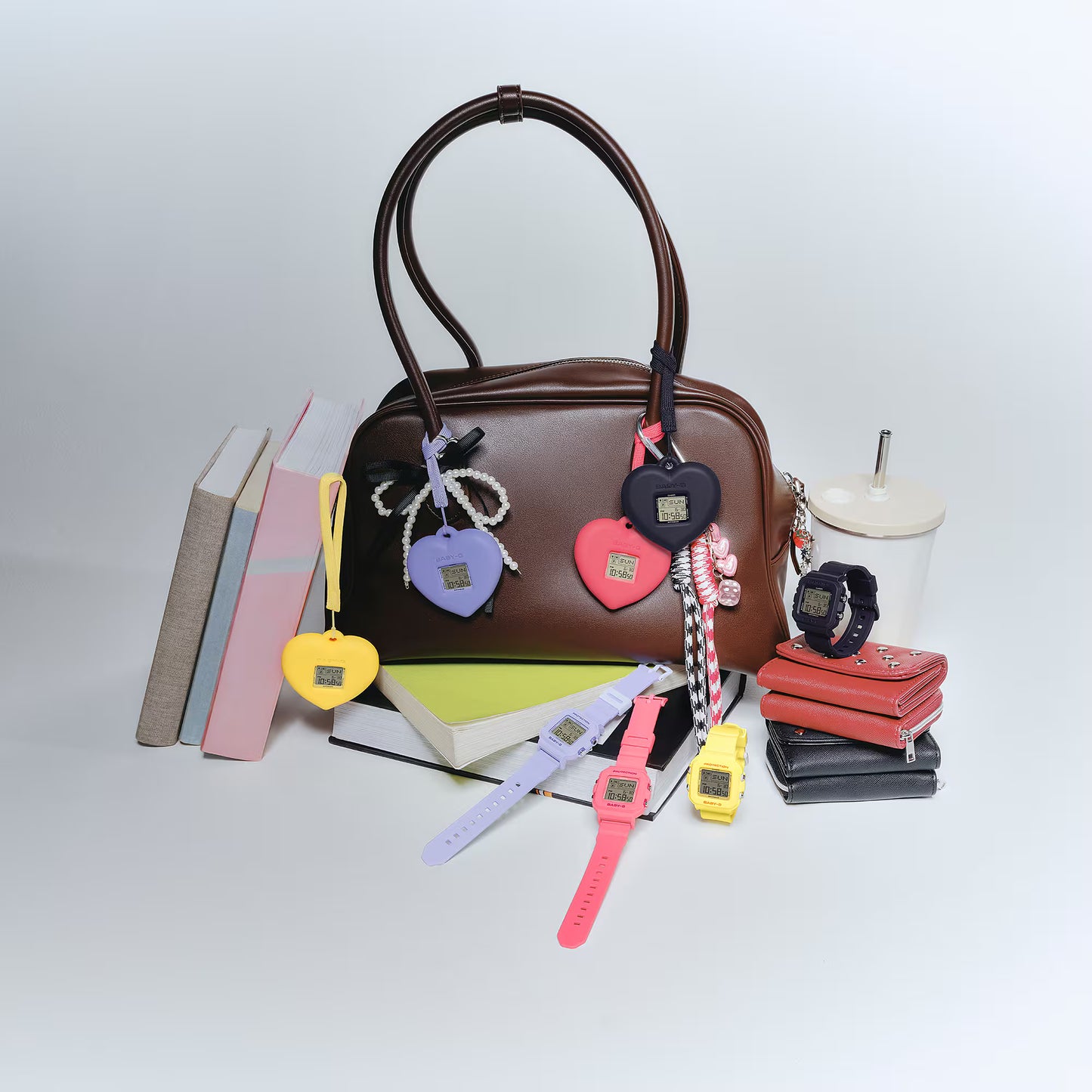 Brown handbag with colorful keychains and watches on a white background