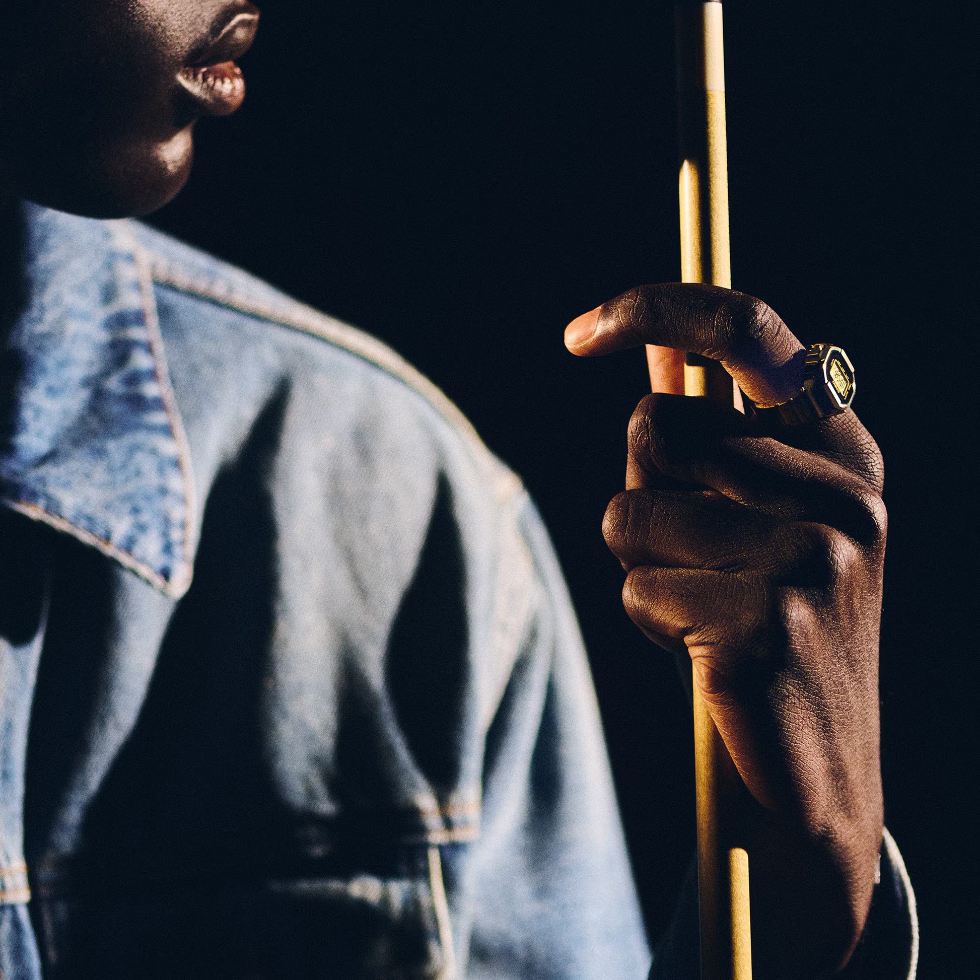 Person holding a pool cue with a dark background