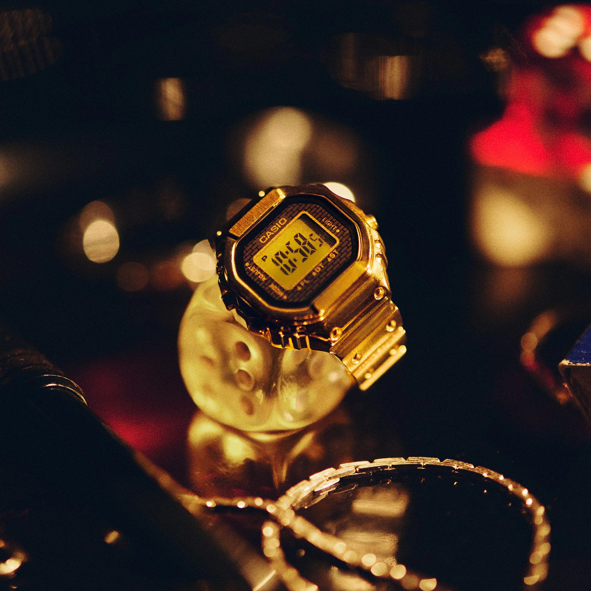 Gold Casio watch on a reflective surface with blurred background