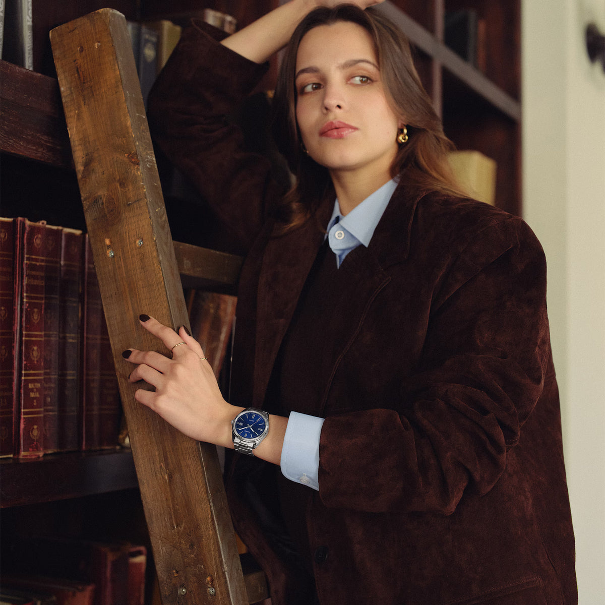 CASIO MTP1302D-2AVT blue dial stainless steel watch styled with a polished outfit in a vintage library setting.