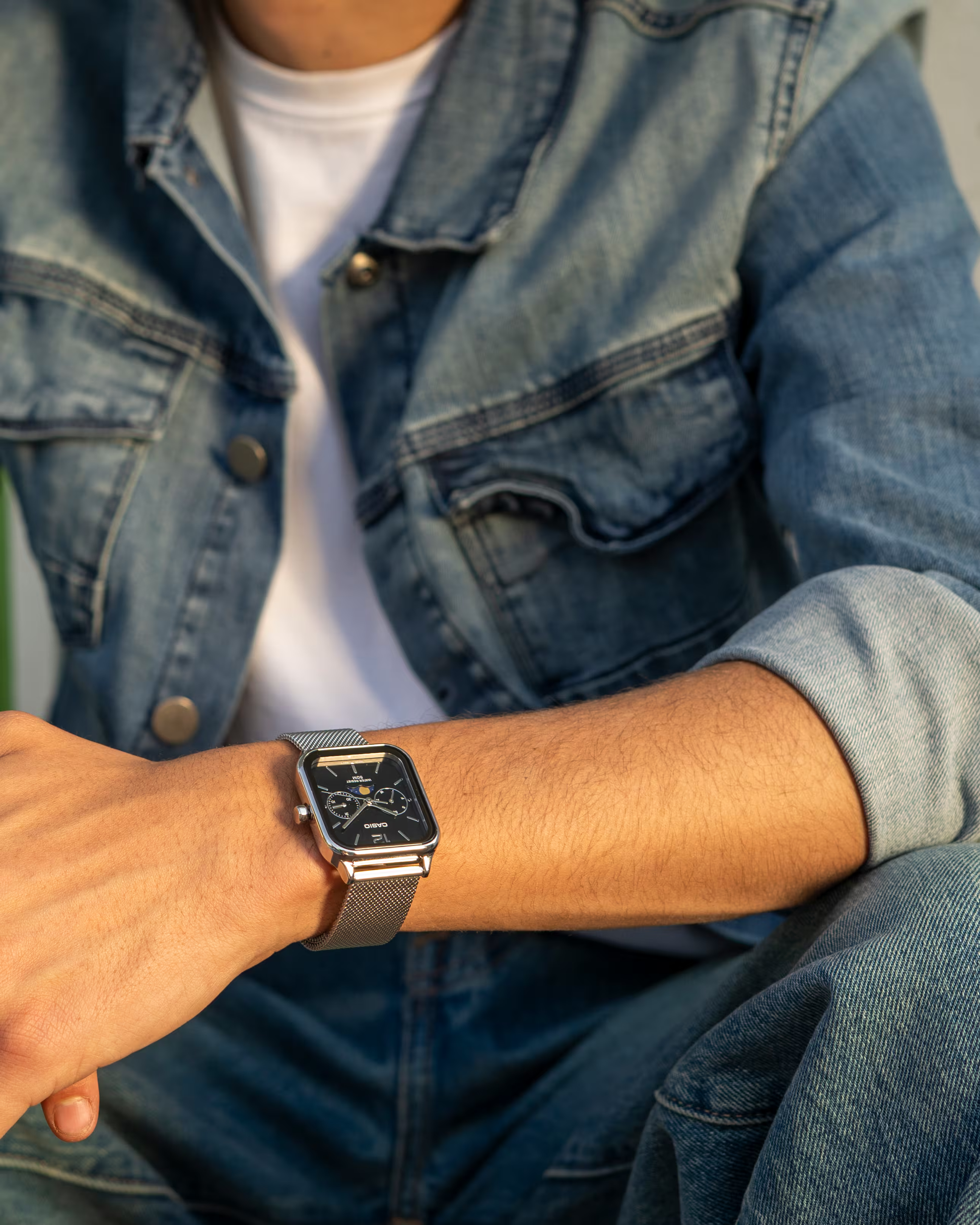 “Casio Standard MTPM305MC-1AV men’s analog watch with stainless steel rectangular case, black dial, moon phase display, date and day sub-dials, mineral glass, 50m water resistance, and stainless steel mesh band.