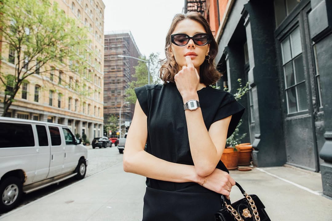 Woman in a black dress and sunglasses on a city street