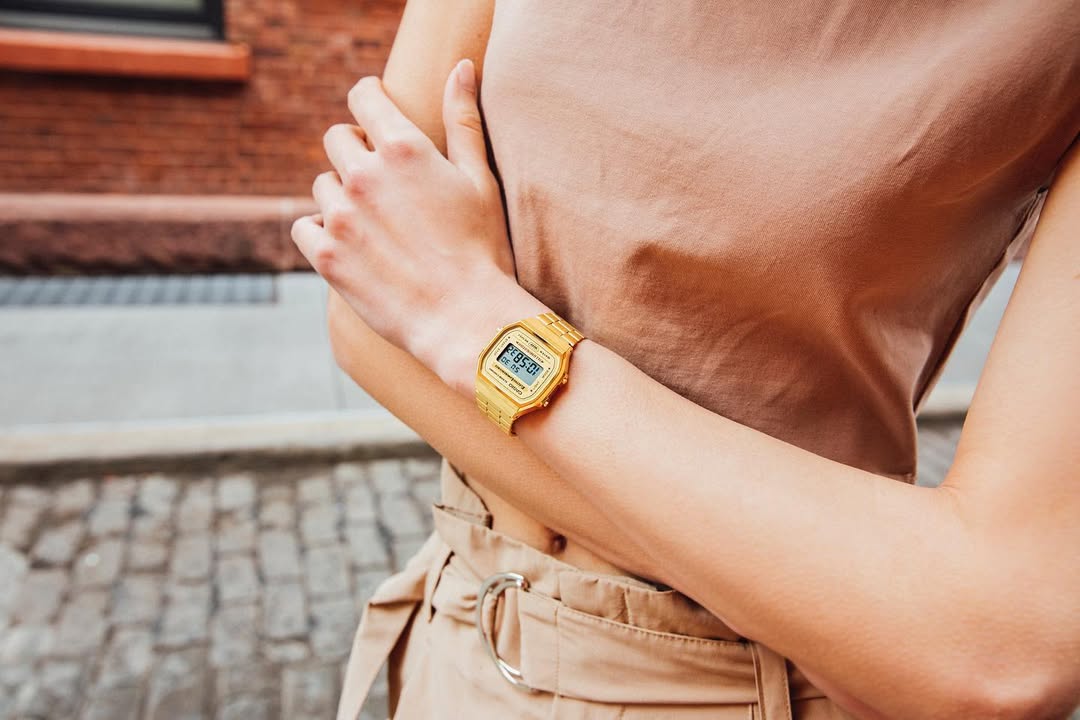 Person wearing a gold wristwatch with a blurred background