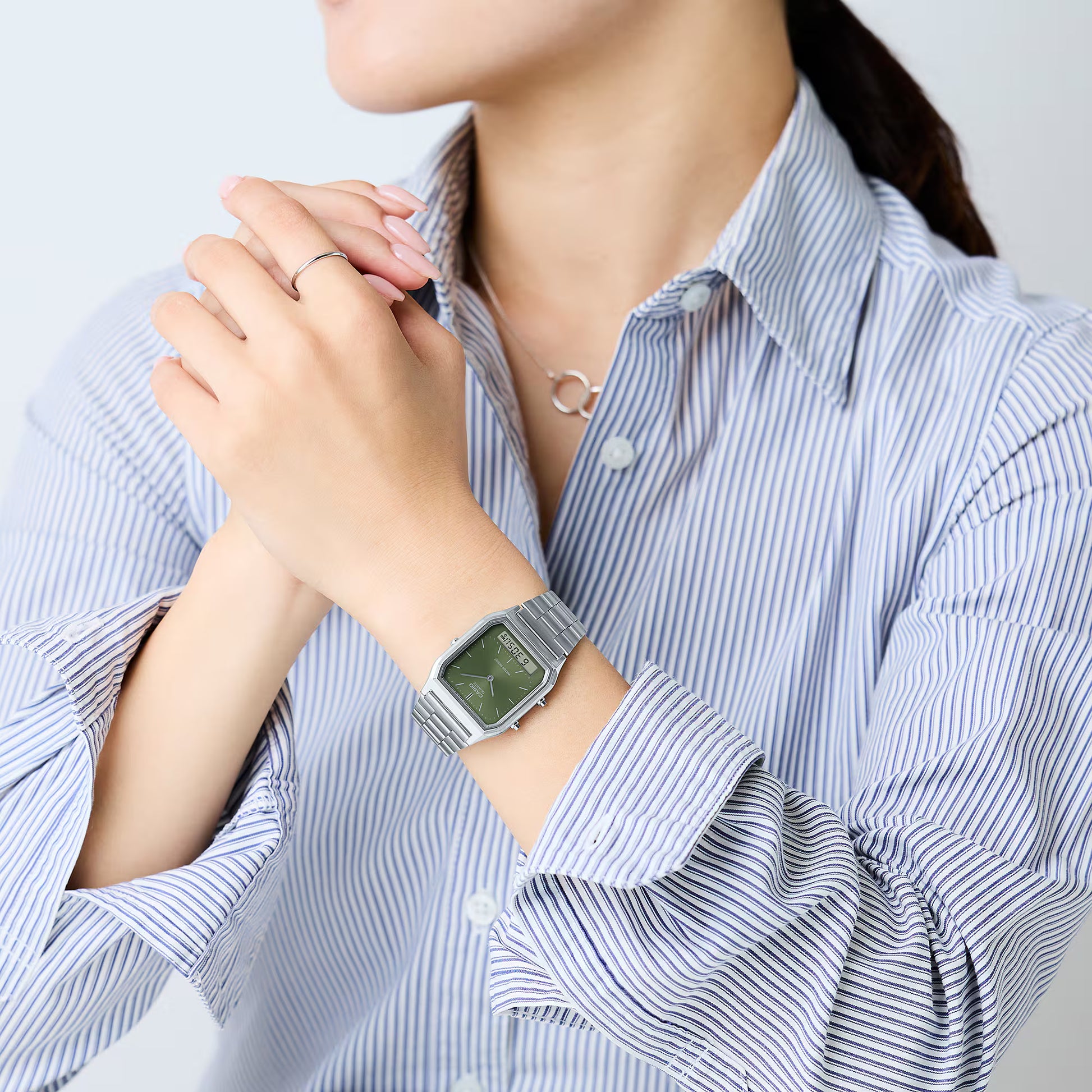 Person wearing a silver watch with a light background