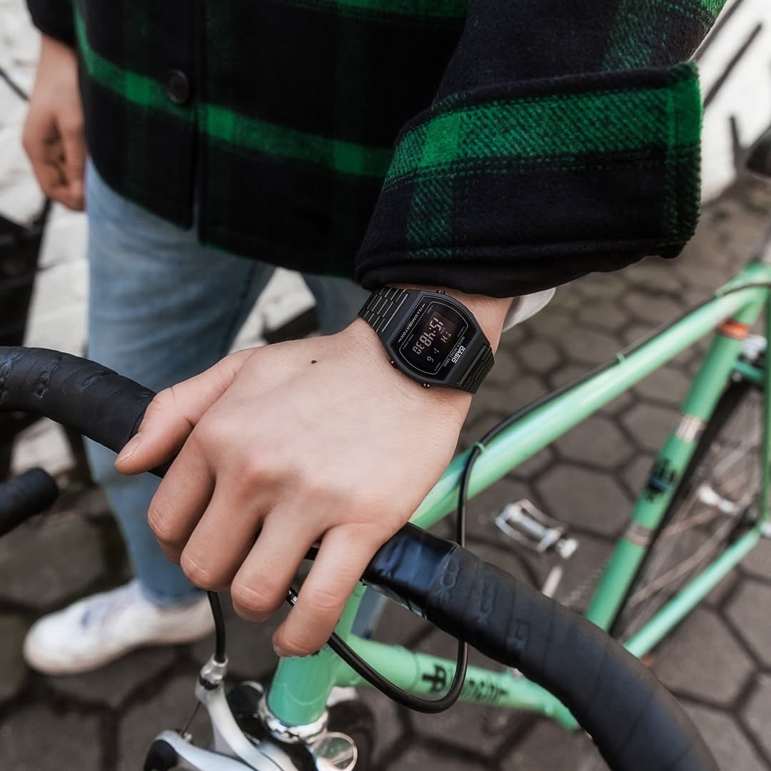 Person wearing a smartwatch on a bicycle handlebar with a blurred background