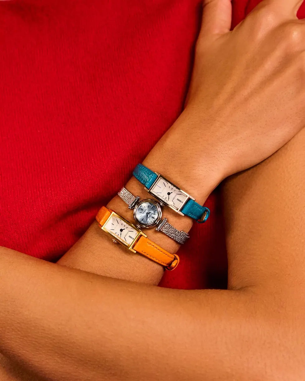Close-up of a wrist wearing multiple bracelets with a red garment in the background